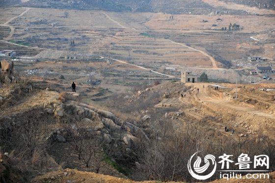 费县崔家沟村，一名村民站在山头看着眼前穷了几百年的沟沟壑壑。如今，通过异地搬迁扶贫，这里的老百姓过上了富裕的生活。