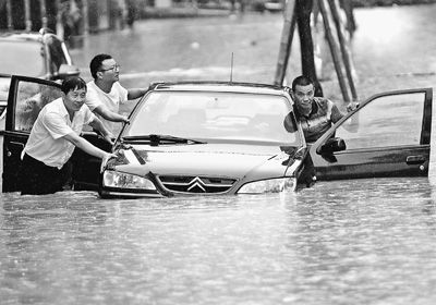 圖為6月15日，市民在江西九江市濂溪區積水路段冒雨涉水前行。