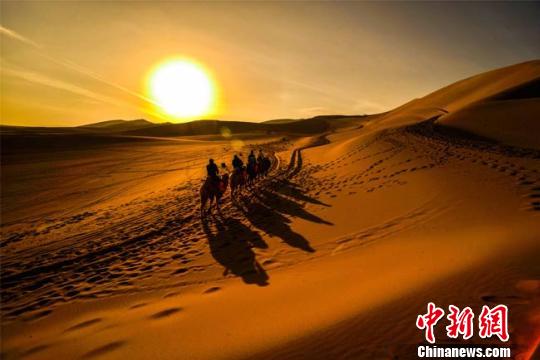 图为初春时节，游客在鸣沙山观赏敦煌大漠日出。　王斌银 摄