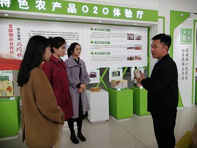 商河县逯家村乡村振兴工作专员陈龙（右）向参观者推介特产核桃油。
